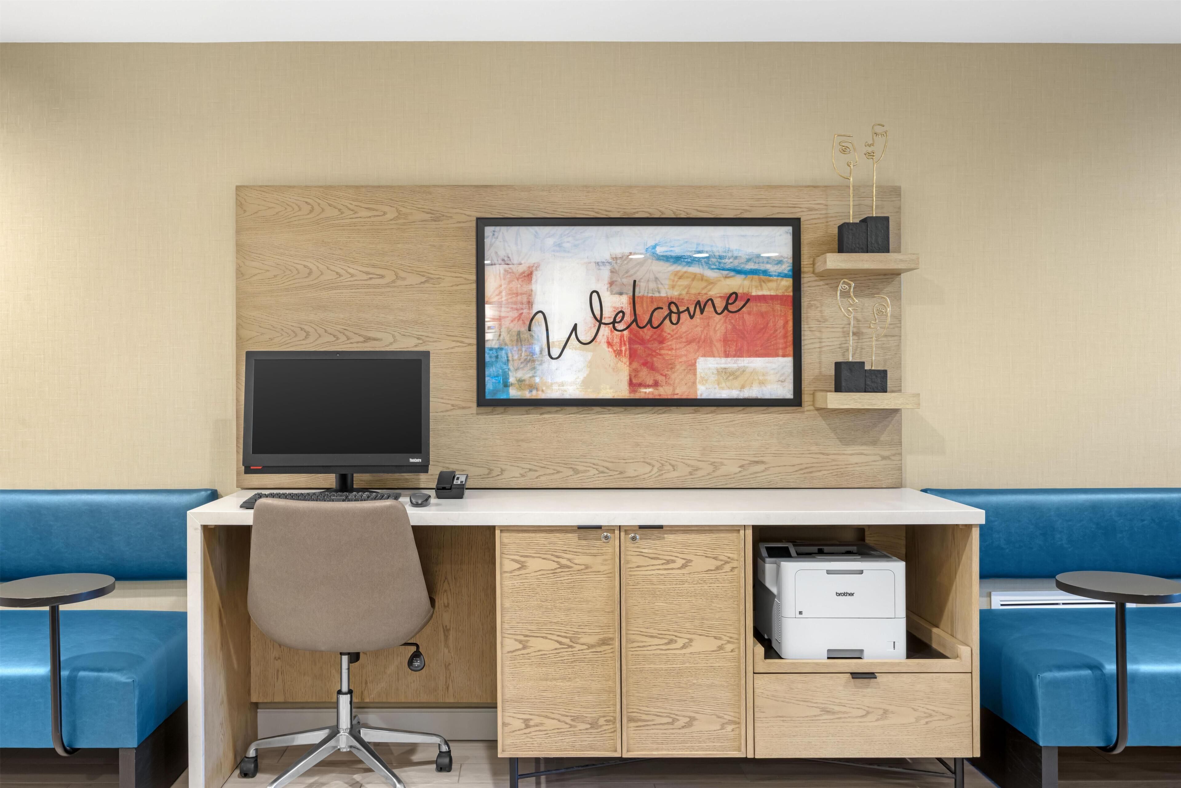 Un ufficio moderno con scrivania, computer, sedia e un cartello con la scritta 'Welcome'.