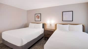 A hotel room with two beds, a nightstand, and two wall-mounted lamps.