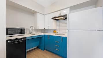 Eine moderne Küche mit weißen Schränken, einer blauen Arbeitsplatte und einem weißen Kühlschrank.