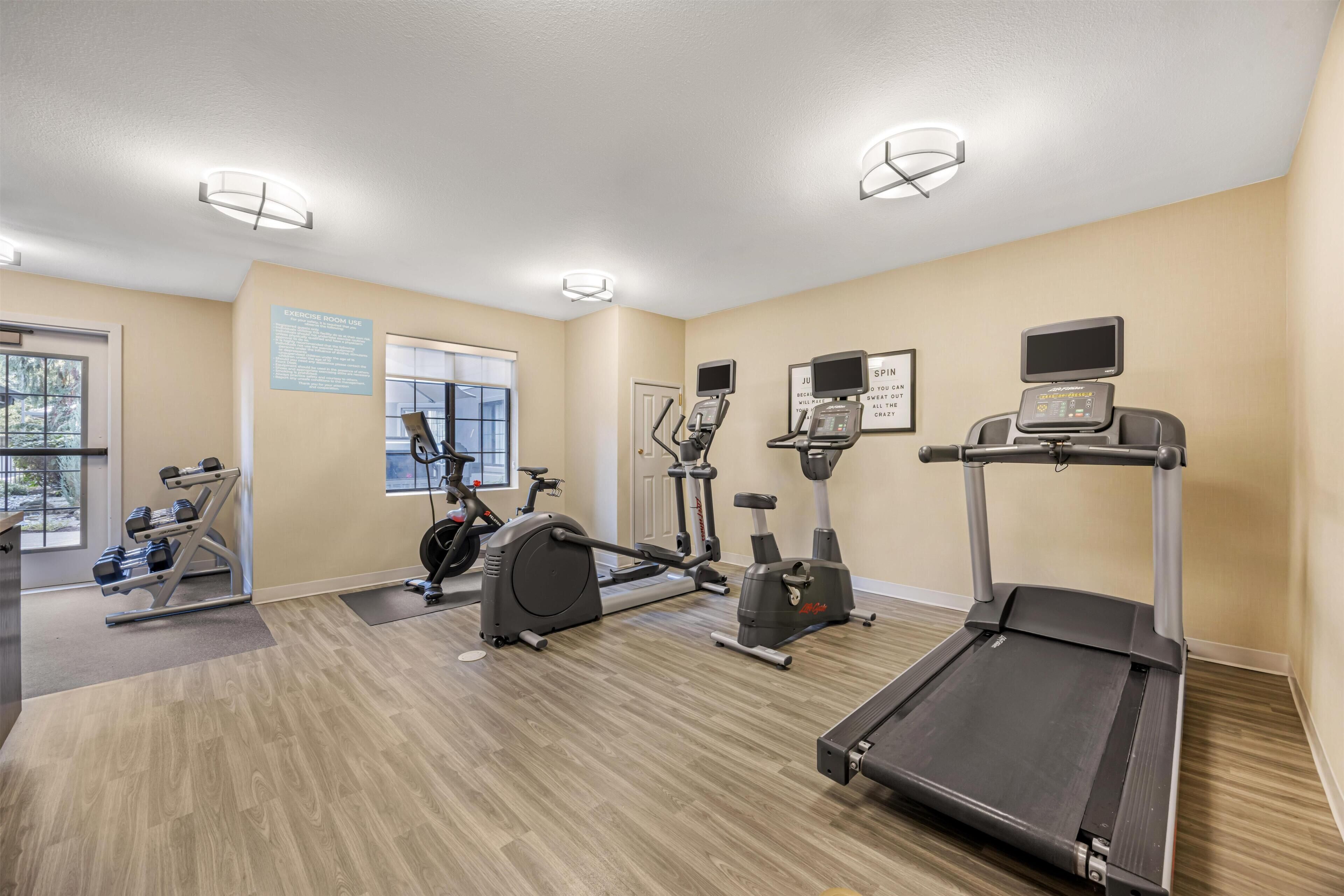 Un gimnasio con cintas de correr, bicicletas estáticas y pesas sueltas.