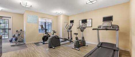 A gym with treadmills, stationary bikes, and free weights.