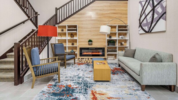 A living room with a fireplace, a staircase, and a bookshelf. - Country Inn & Suites by Radisson, Pickerington, OH (Pickerington)