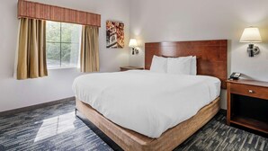 A hotel room with a large bed, two bedside lamps, a nightstand, a window with curtains, and a wall-mounted artwork. - Country Inn & Suites by Radisson, Pickerington, OH (Pickerington)