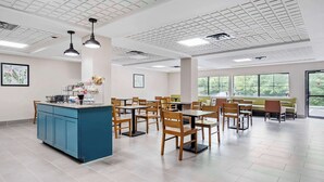 A spacious dining area with high ceilings, large windows, and a central island with a blue countertop. - Country Inn & Suites by Radisson, Pickerington, OH (Pickerington)