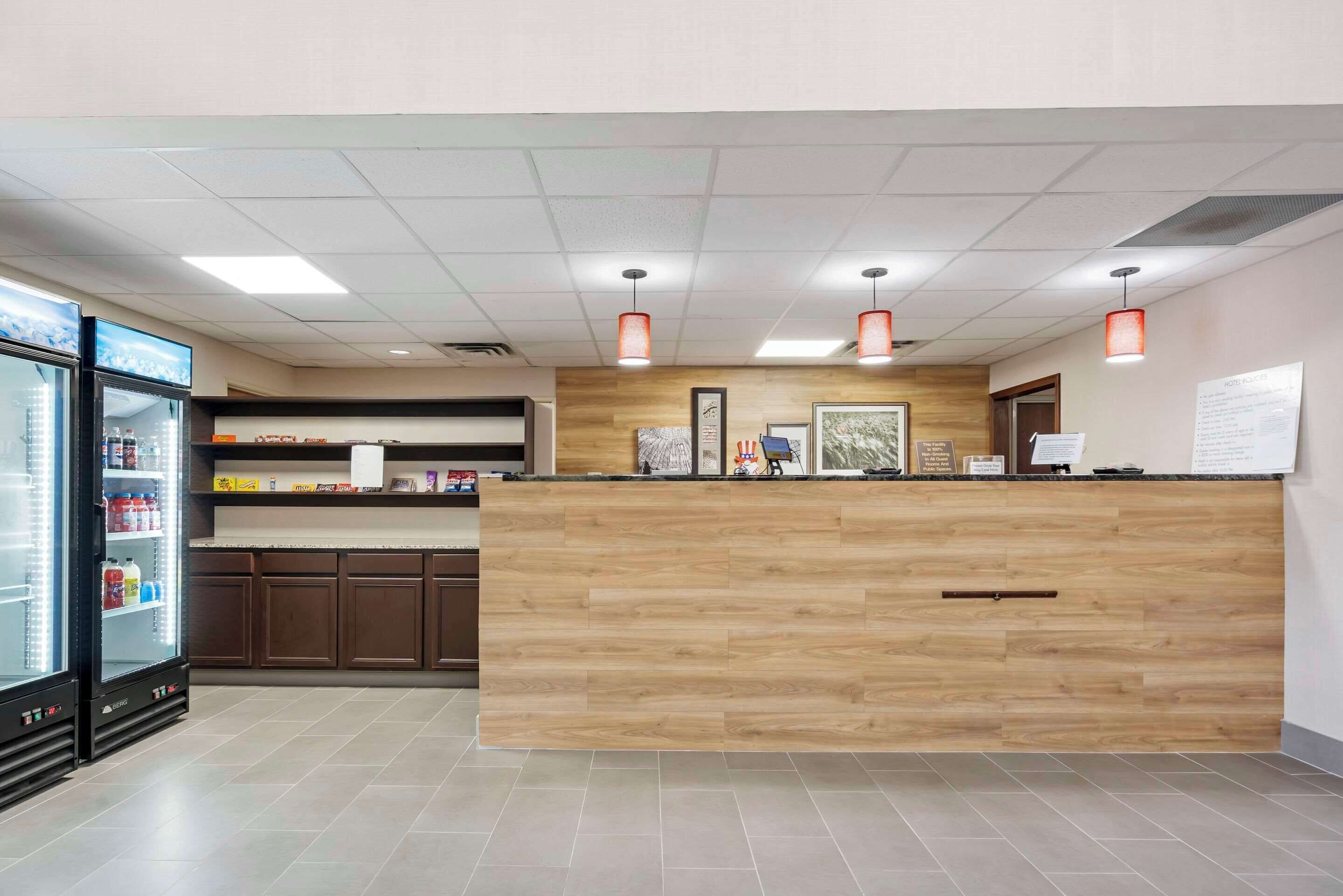 A reception area with a wooden counter, a refrigerator stocked with beverages, and a whiteboard with information.