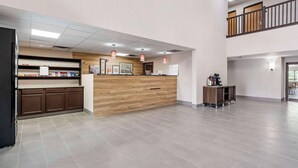 A reception area with a wooden counter, a refrigerator, and a small table with a coffee machine. - Country Inn & Suites by Radisson, Pickerington, OH (Pickerington)