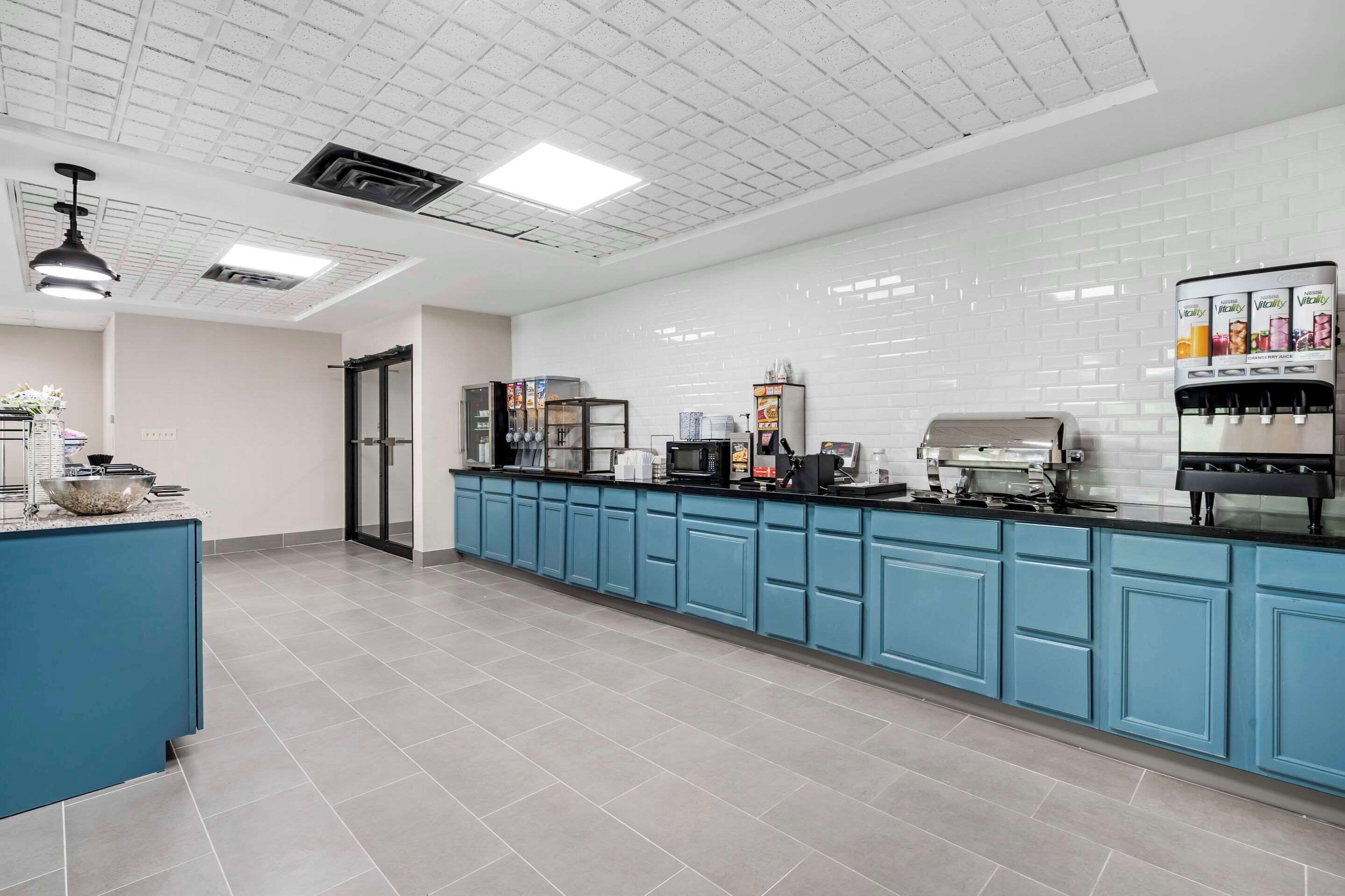 A modern kitchen with blue cabinets, a coffee station, and a refrigerator.