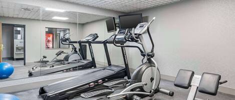 Un gimnasio con cintas de correr, máquinas elípticas y pesas libres.