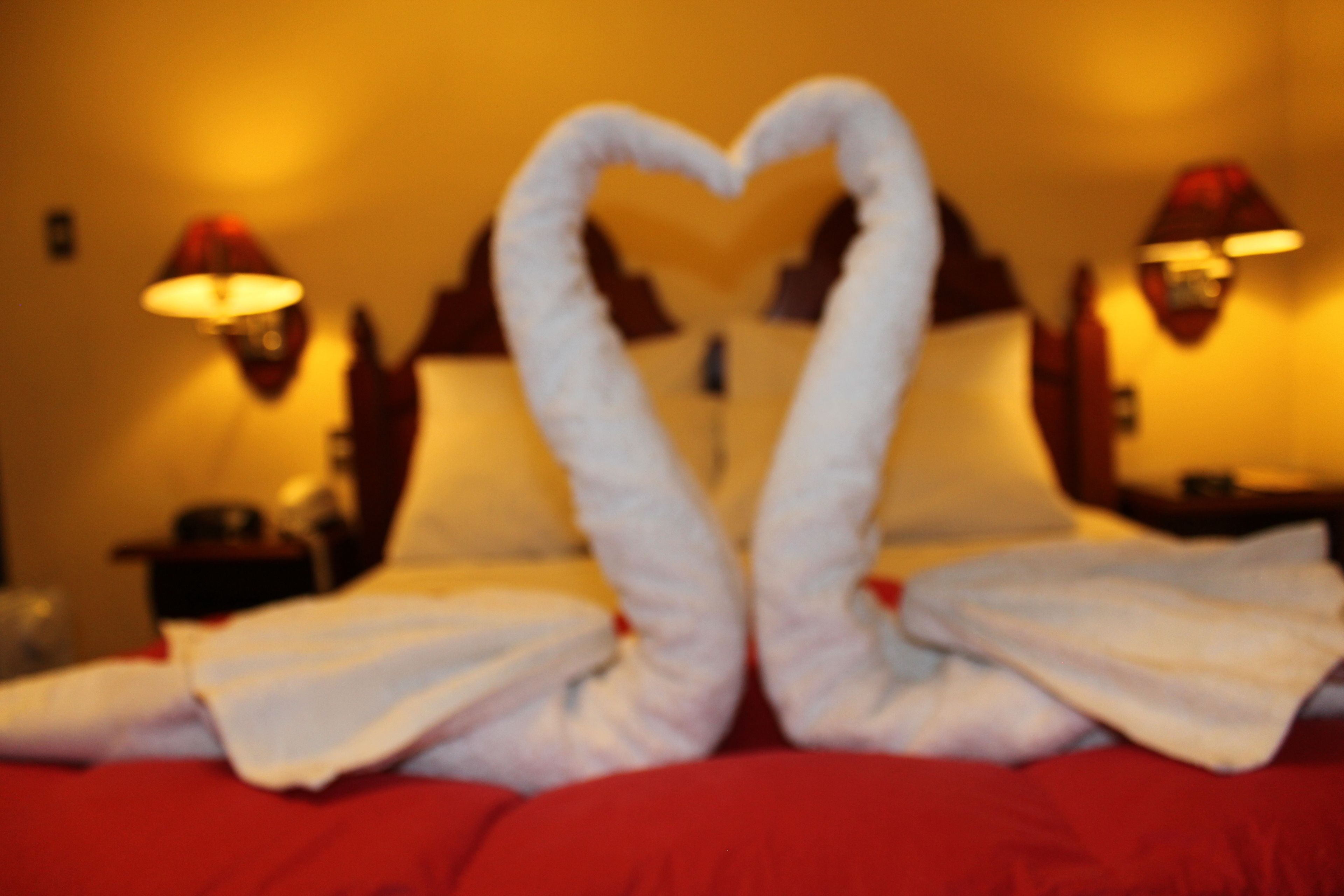 A bed with a heart-shaped towel arrangement.