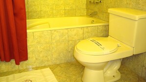Un baño con bañera, inodoro y una cortina roja.