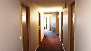 A long, narrow hallway with doors on both sides, leading to individual rooms. - Hotel Kiotel Lyon Bron Eurexpo (Bron)
