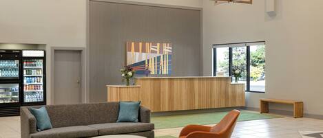A modern lobby with a reception desk, a sofa, a rocking chair, and a coffee table.