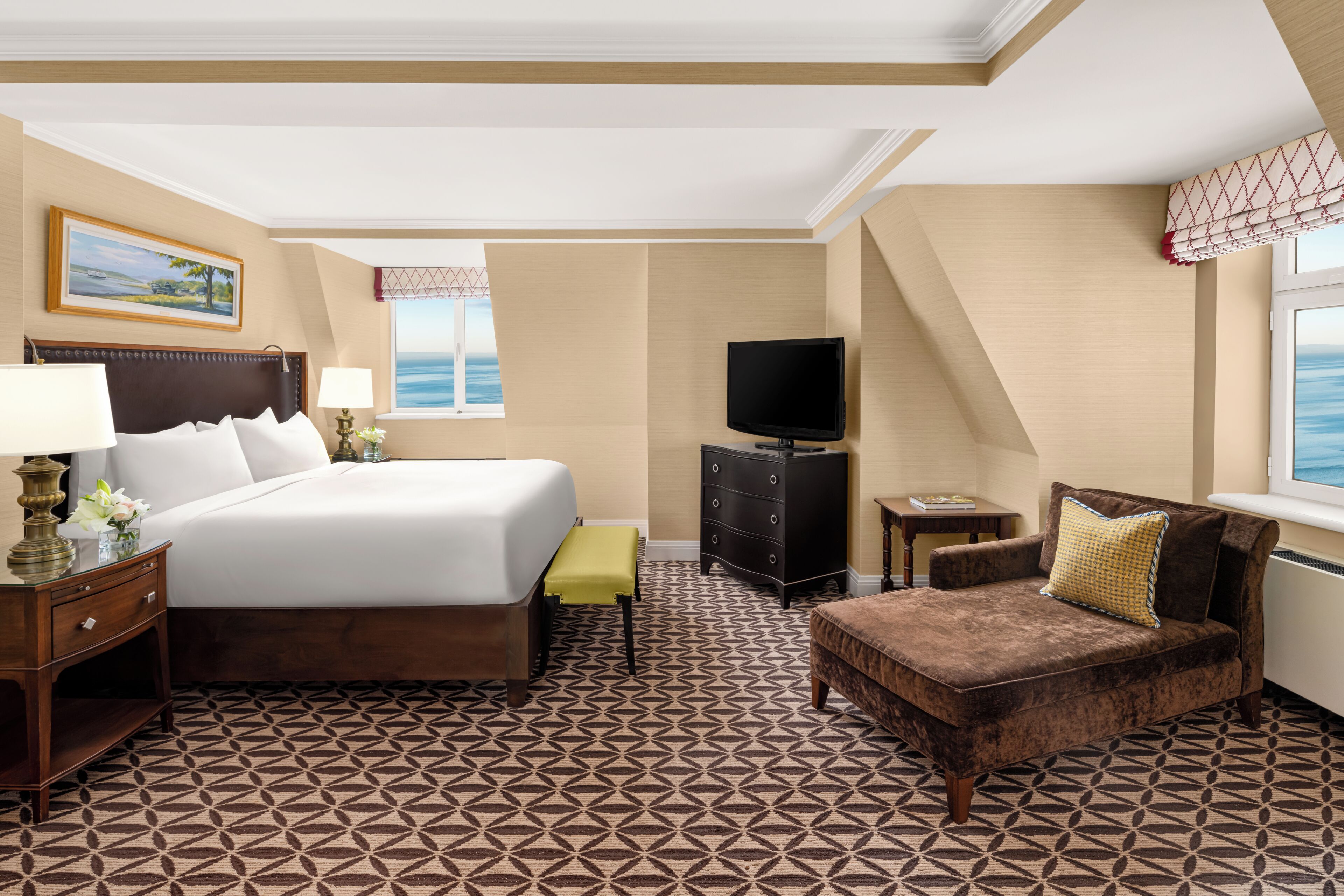 A hotel room with a bed, a television, a dresser, a chair, and a window with a view.