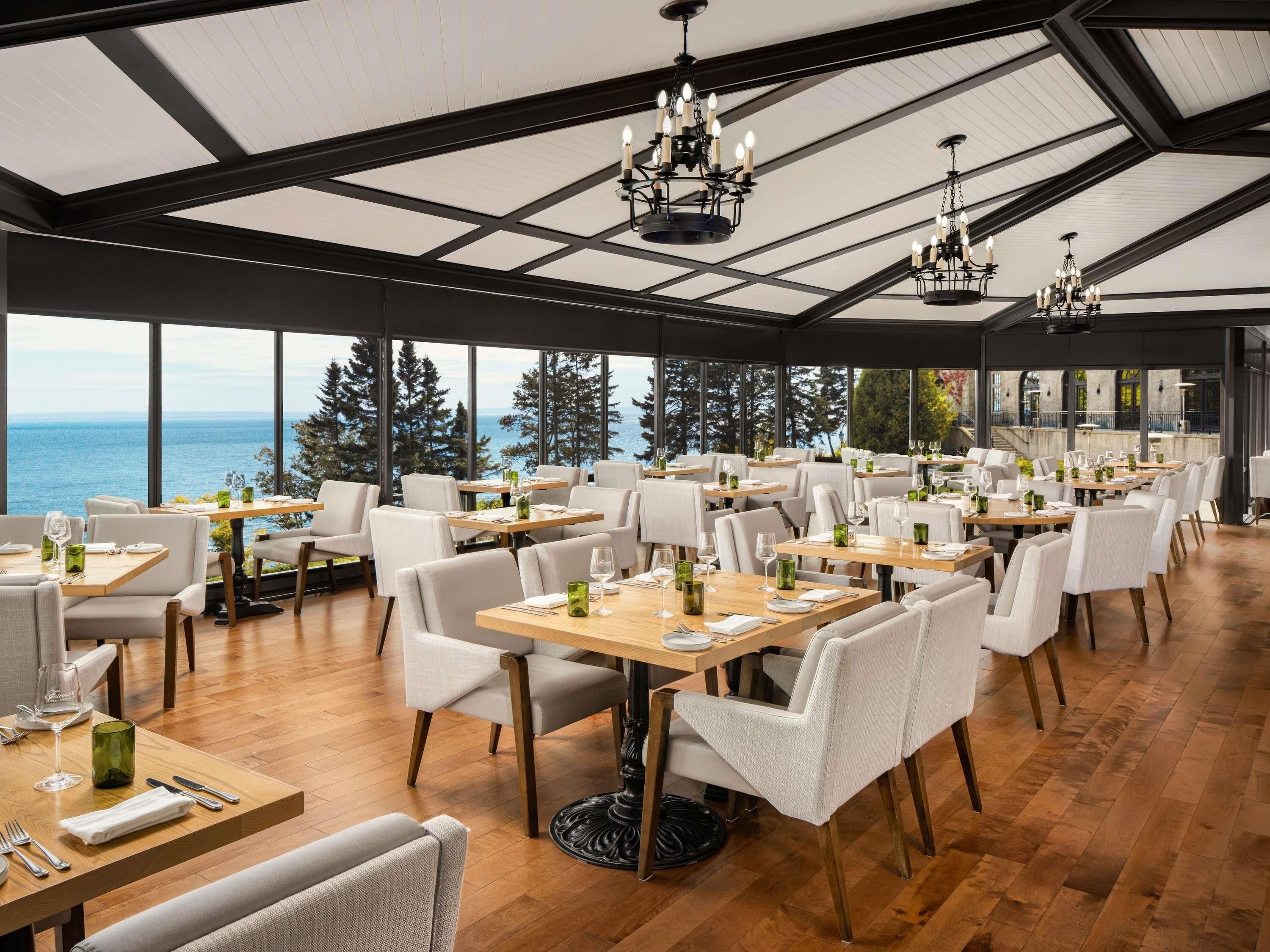 A restaurant with multiple tables, chairs, and chandeliers.