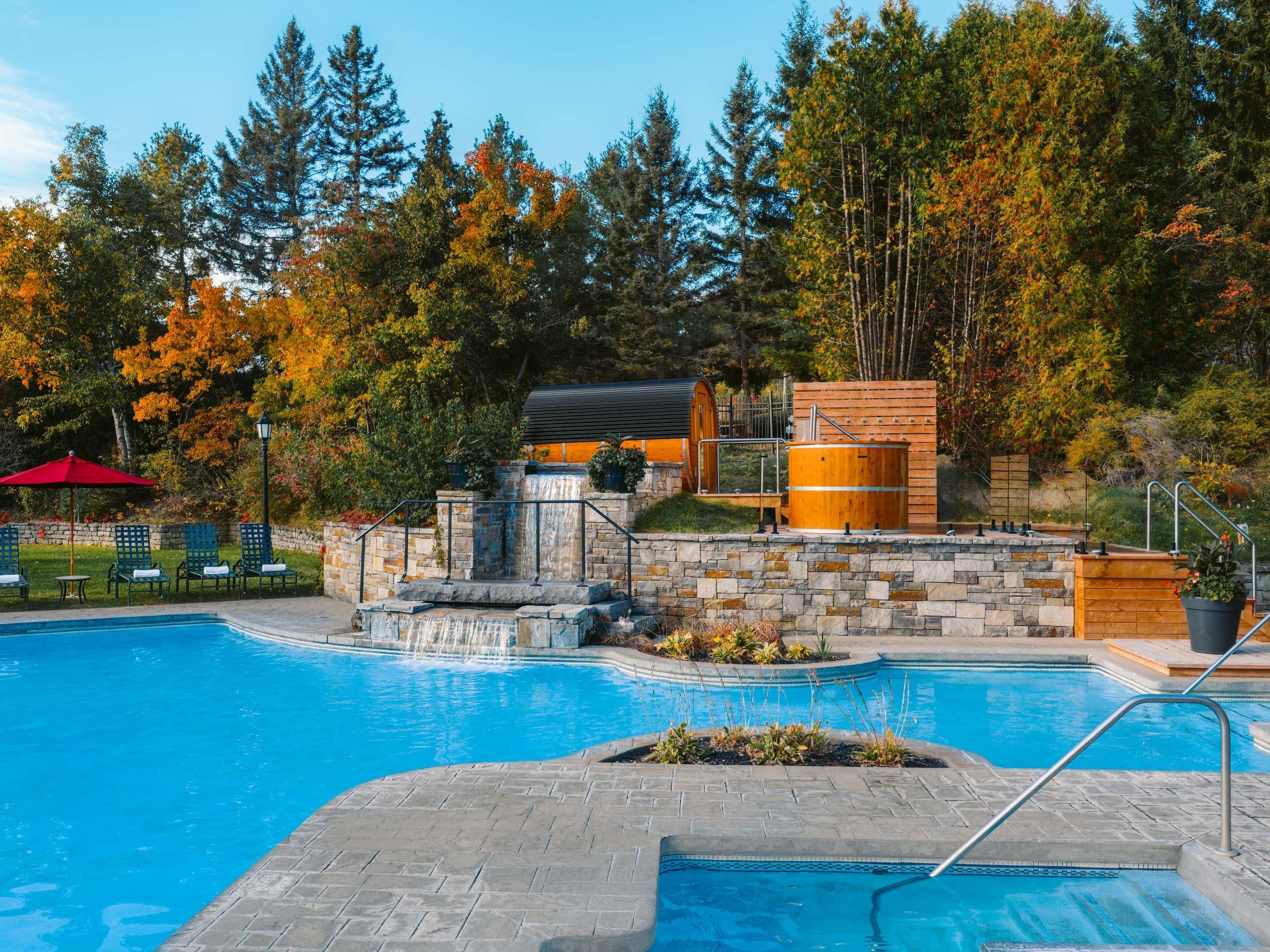 Una piscina con cascada, rodeada de muros de piedra y estructuras de madera.