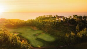 An aerial view of a golf course with a clubhouse and a road leading to it. - Fairmont Le Manoir Richelieu (La Malbaie)