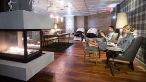 A modern lounge area with a fireplace, seating, and a table with a laptop. - Fairmont Le Manoir Richelieu (La Malbaie)