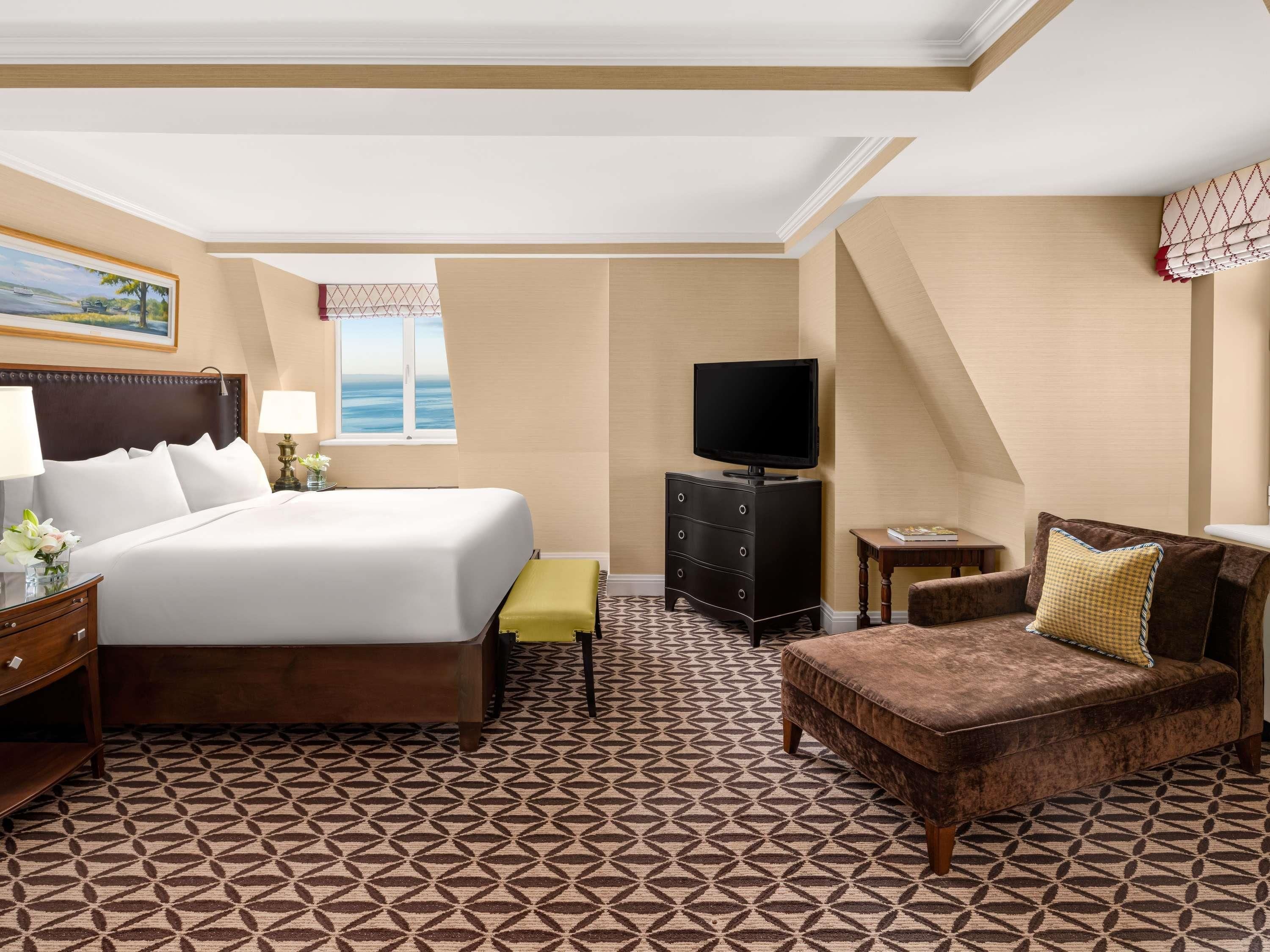 Une chambre d’hôtel avec un lit, une télévision, un canapé et une moquette à motifs.