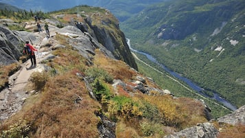 A rocky hiking trail with hikers and a river valley in the background.