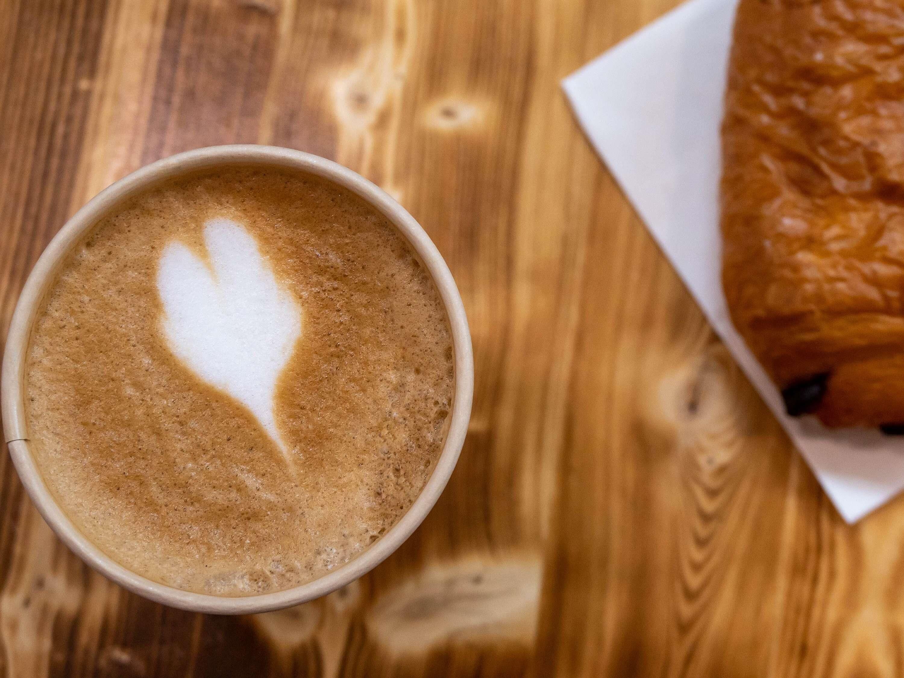 A cup of coffee with latte art on a wooden table.