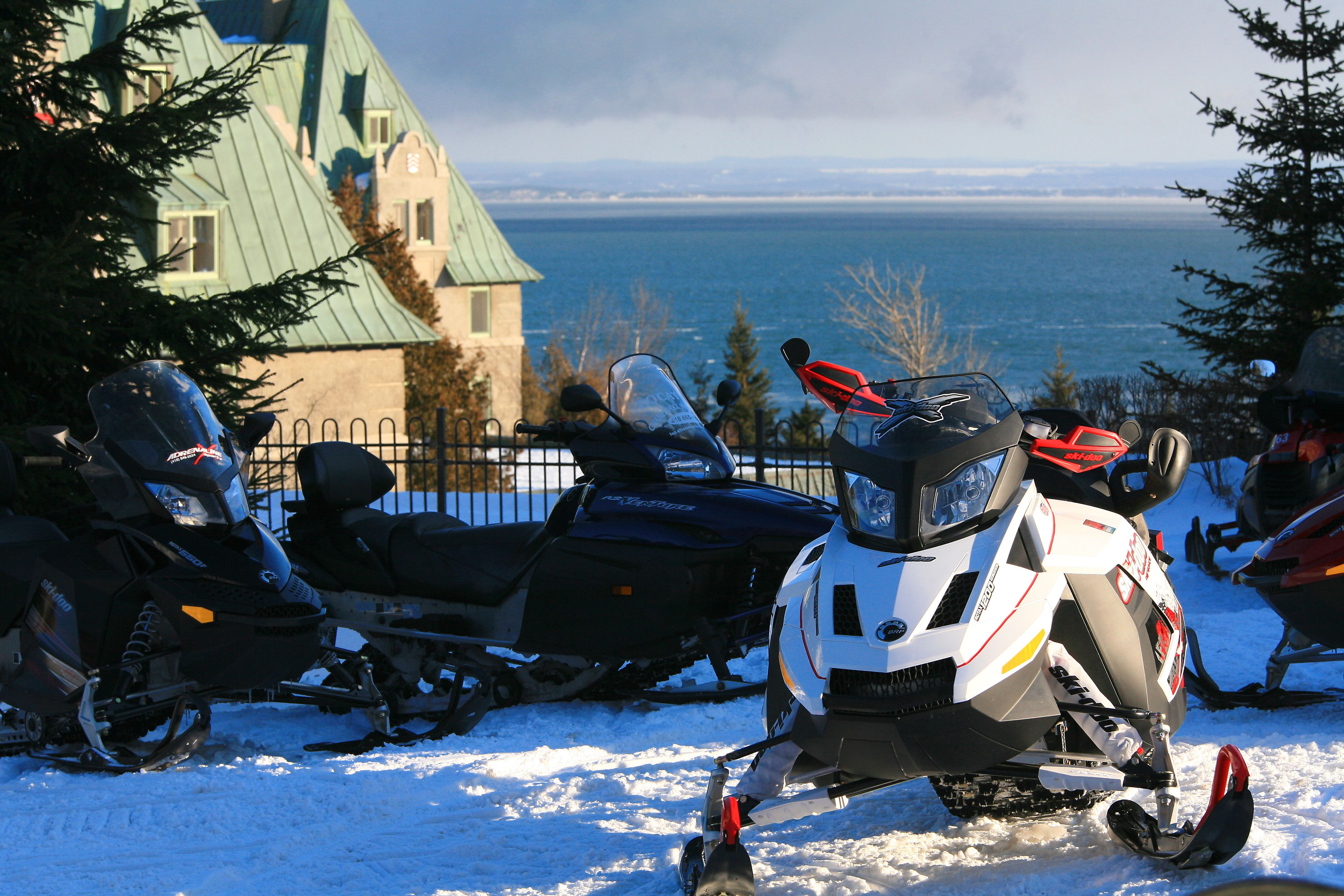 A snow-covered landscape with a view of the ocean and a building with a green roof.