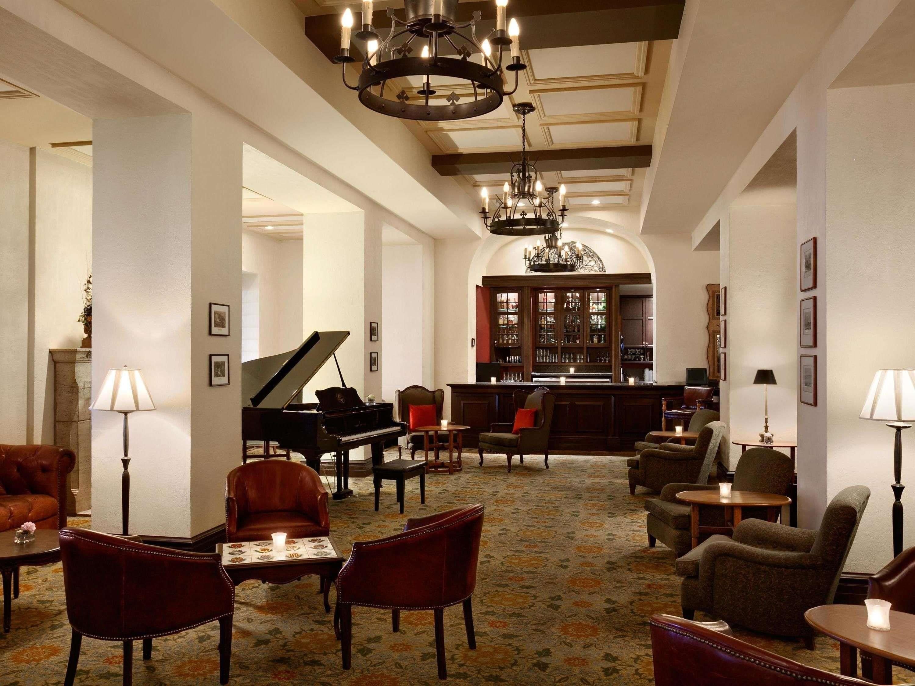 Un'ampia hall con un pianoforte a coda, comodi posti a sedere, un'area bar e un lampadario.