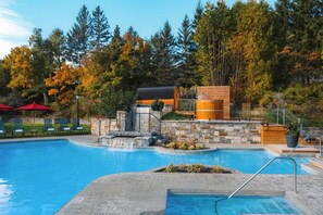 A swimming pool with a waterfall feature, surrounded by stone walls and wooden structures. - Fairmont Le Manoir Richelieu (La Malbaie)