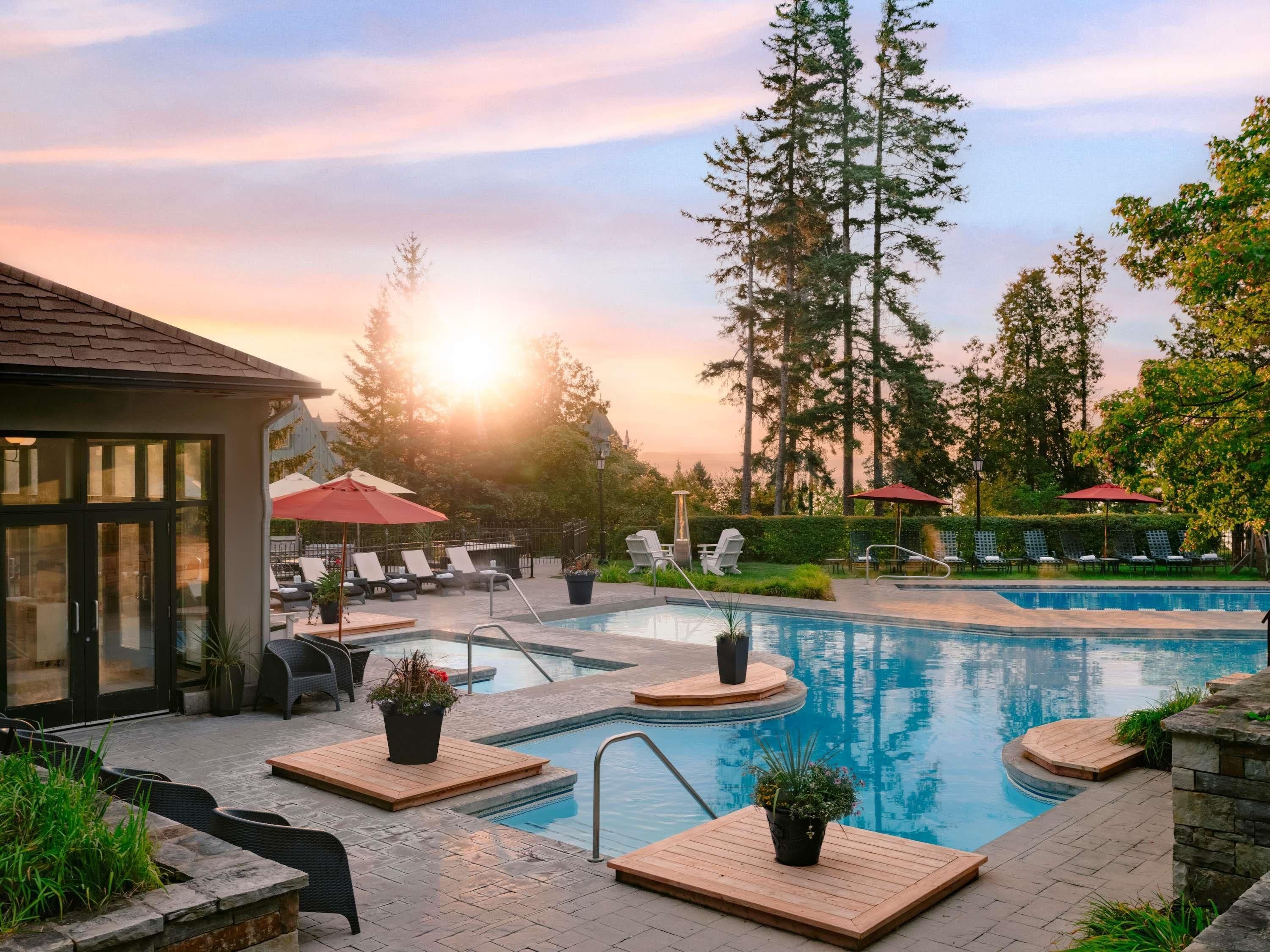 A pool area with lounge chairs, a wooden deck, and a building with glass doors.
