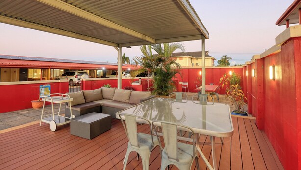 An outdoor patio area with a covered seating area, a table, and chairs.