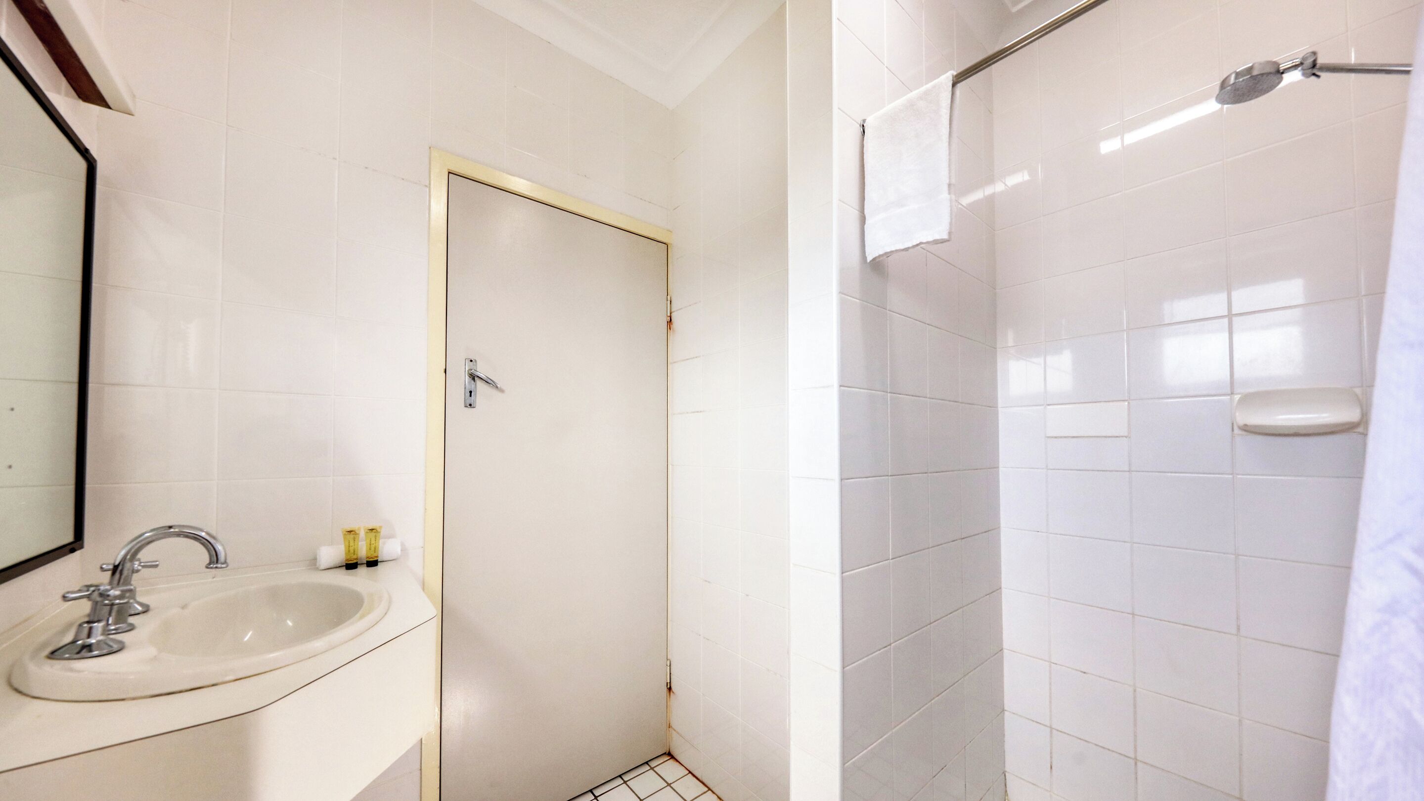 Une salle de bain avec un lavabo, une porte et un espace douche.