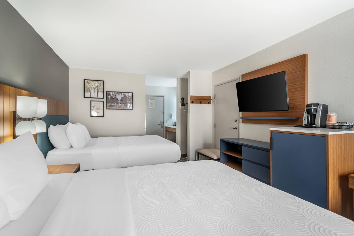 Hotellihuone, jossa on kaksi sänkyä, televisio, kahvinkeitin ja työpöytä.