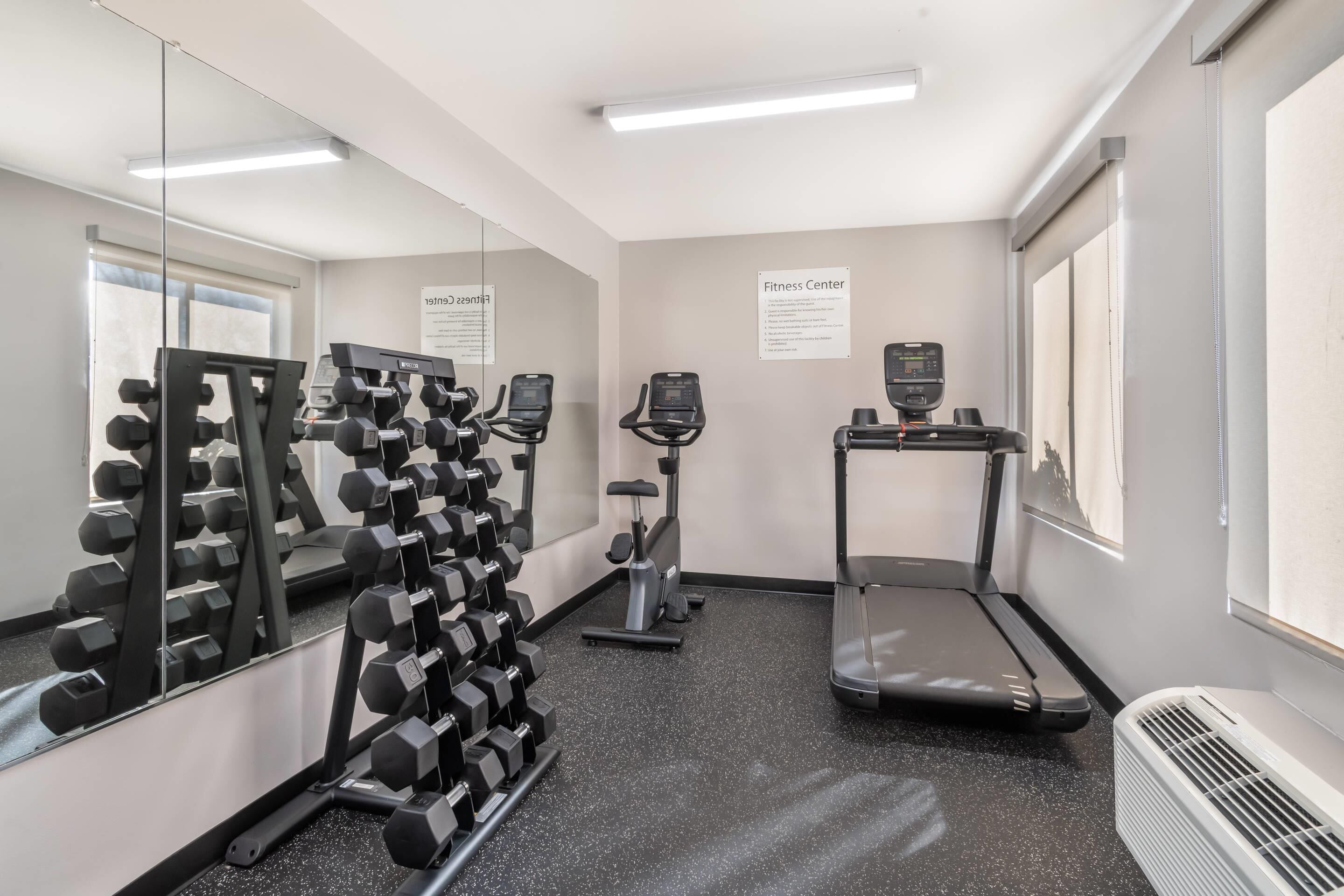 A fitness center with dumbbells, treadmills, and exercise bikes.