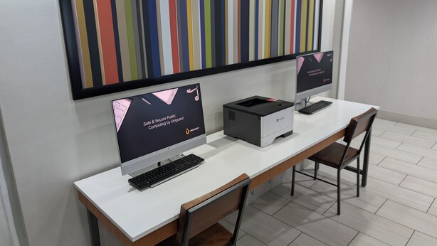 Een moderne kantoorruimte met twee bureaus, elk met een computer en toetsenbord.