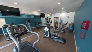 Een sportschool met loopbanden, elliptische trainers en een hometrainer.