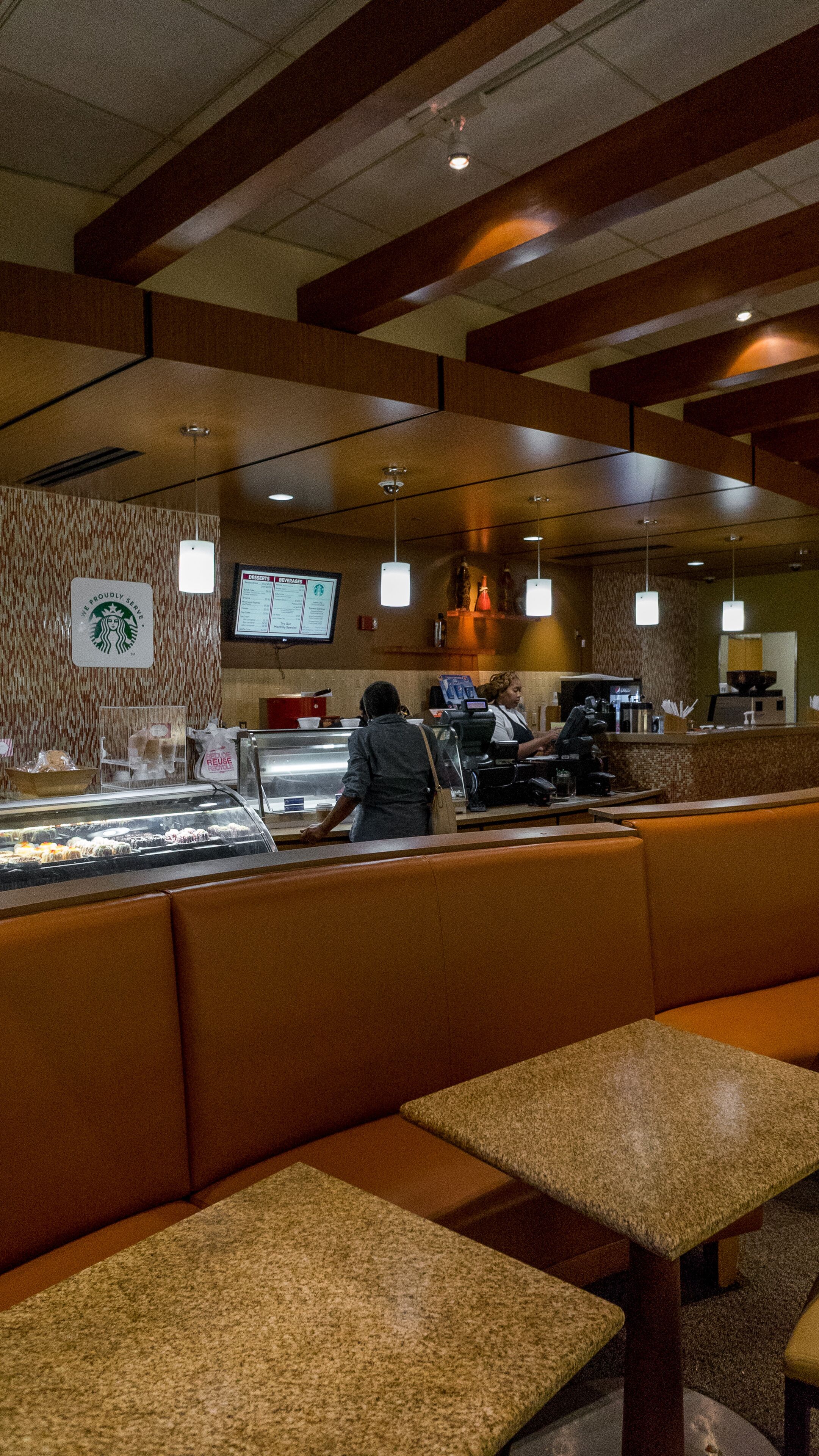 A restaurant interior with a counter, seating area, and a menu board.