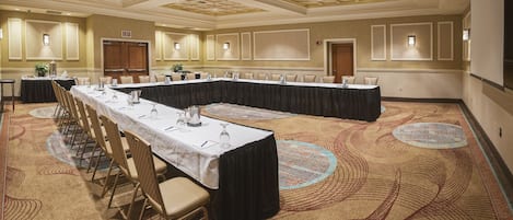A conference room with a long table, chairs, and a carpeted floor.