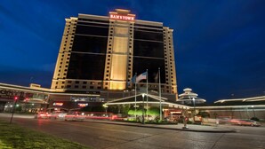 A high-rise hotel with a prominent "SAMSTOWN" sign, multiple floors, and a well-lit entrance area.