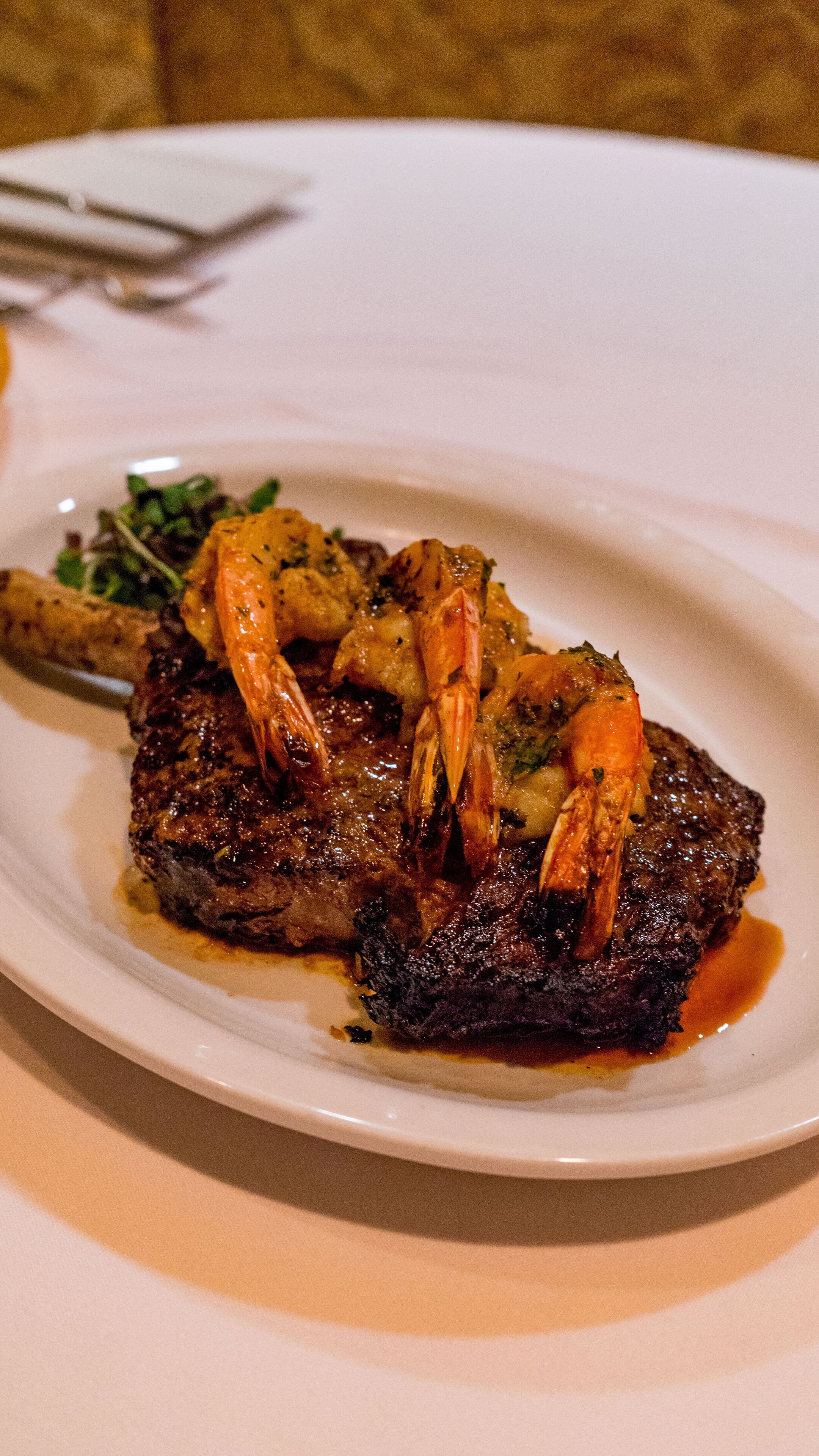 Un plato de comida con carne, camarones y vegetales.