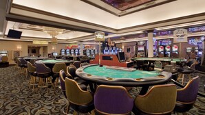 A casino floor with multiple blackjack tables, slot machines, and a sign indicating restrooms.