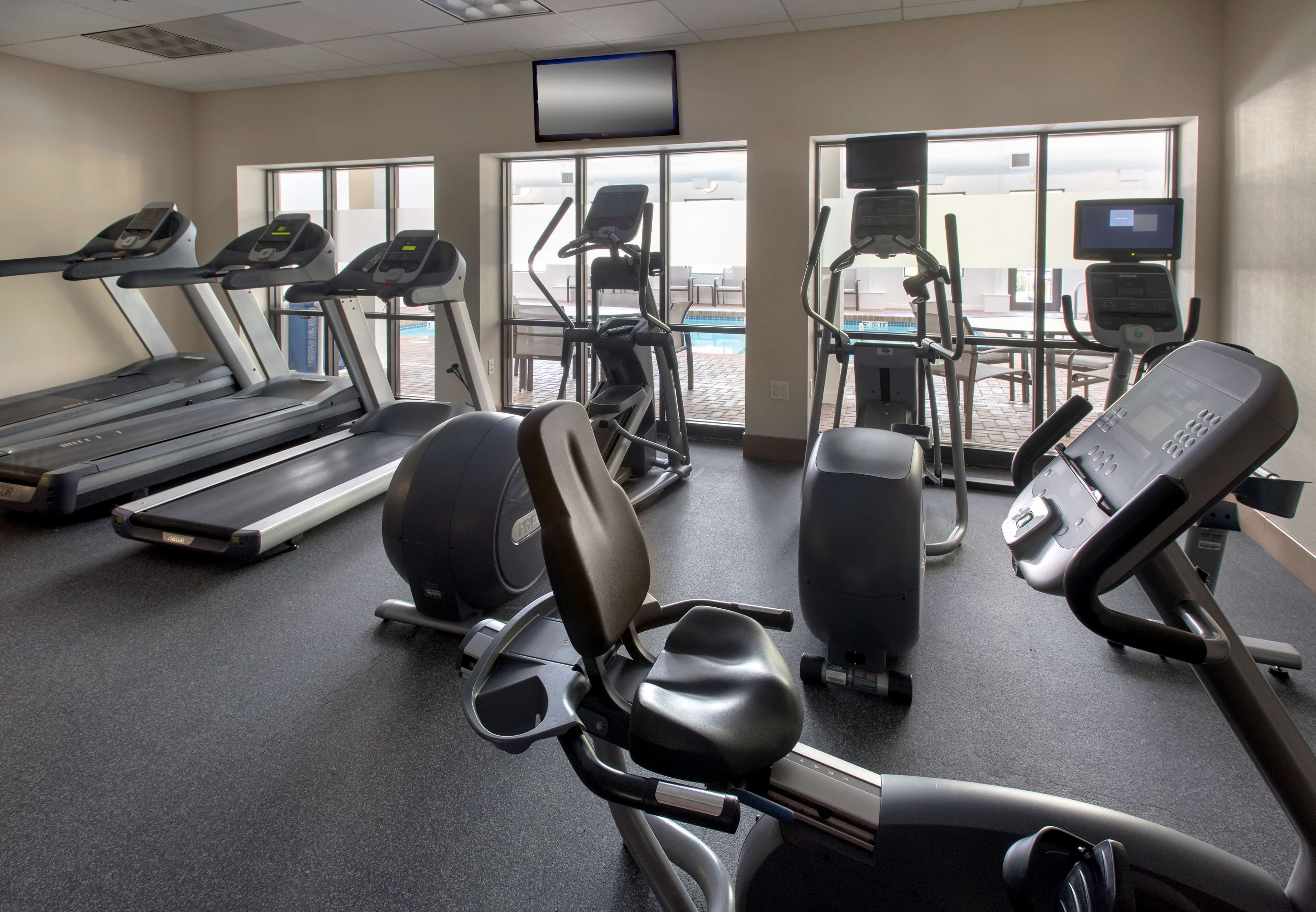 Une salle de sport équipée de tapis de course, d’appareils elliptiques et de vélos d’appartement.