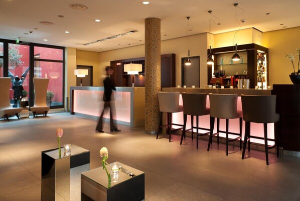 Un moderno vestíbulo de hotel con una recepción, zona de bar y asientos.