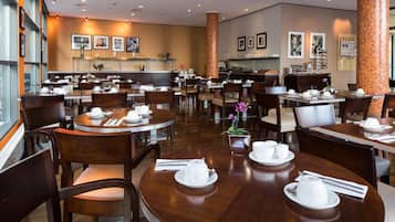 A spacious restaurant with multiple round tables, each set with white dishes and napkins.