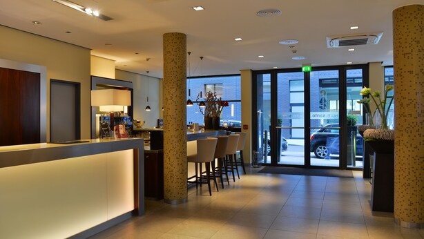 Un vestíbulo de hotel con recepción, zona de bar y asientos.
