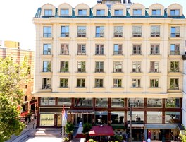 A multi-story hotel with a symmetrical facade, large windows, and a central entrance with a red awning.