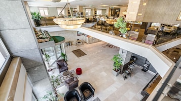 A hotel lobby with a high ceiling, multiple seating areas, and a central staircase.