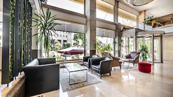 A spacious lobby with modern furniture, large windows, and indoor plants.