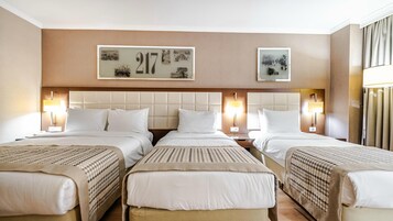 Habitación de hotel con tres camas, el número grande '217' en la pared y obras de arte sobre cada cama.