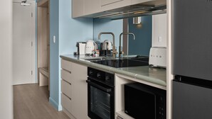 A modern kitchen with a built-in oven, a refrigerator, and a sink with stainless steel faucets. - Adina Sydney Darling Harbour (Sydney)