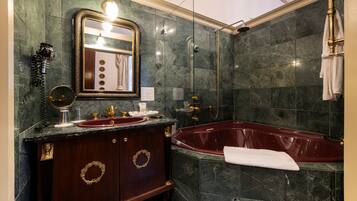 A bathroom with a marble sink, vanity, and a freestanding bathtub.