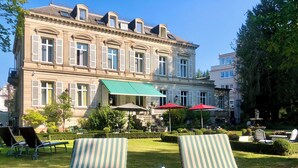 A large, historic building with a courtyard featuring outdoor seating and a fountain.